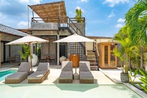 a villa with a swimming pool with two lounge chairs and umbrellas at Kano Twin in Canggu
