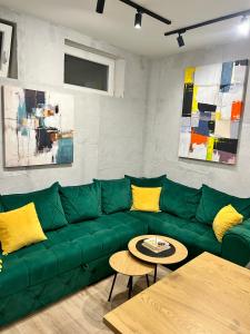 a green couch in a living room with yellow pillows at Industrial Hostel Vila Jovana in Odžaci