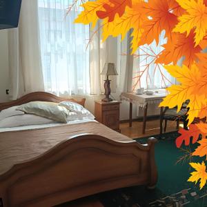 a bedroom with a bed with autumn leaves on the wall at Hotel Jagielloński in Sanok