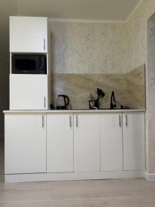 une cuisine avec des armoires blanches et un réfrigérateur blanc dans l'établissement 2х-ком апартаменты в центре города Kvant, à Petropavlovsk-Kamtchatski