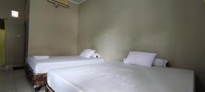 EnrekangにあるOYO 93051 Wisma Syariah Buloe Near Lapangan Abubakar Lambogo Batili Enrekangの白いシーツが敷かれた部屋にベッドが2つ