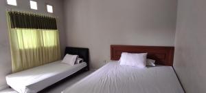 EnrekangにあるOYO 93051 Wisma Syariah Buloe Near Lapangan Abubakar Lambogo Batili Enrekangの白いシーツが敷かれた部屋にベッドが2つ