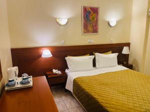 a hotel room with a bed with a yellow bedspread at Triton Hotel Piraeus in Piraeus