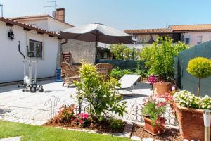 a patio with an umbrella and chairs and flowers at House Nicol Fazana in Fažana