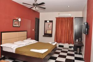 una camera da letto con un letto con pareti rosse e un pavimento a scacchi di Sri ArulMuthu Residency a Madurai