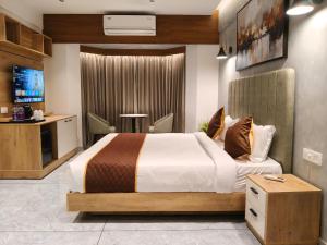 a hotel room with a bed and a tv at Mayo Suites in Palakkad