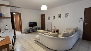 Una sala de estar con un sofá blanco y un televisor. en Condo-Micio Luna, en Azzano