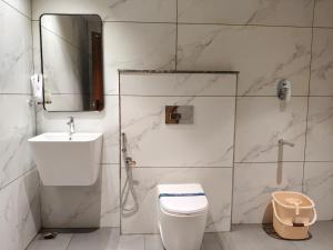 Un baño con inodoro, lavabo y espejo. en Mayo Suites, en Palakkad