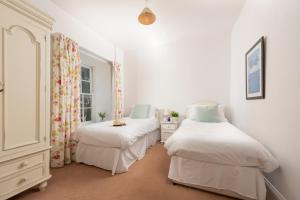two beds in a room with white walls at Stable House in Redruth