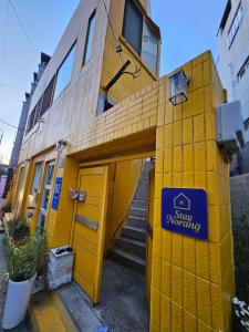 a yellow building with a blue sign on it at 스테이 노랑 stay norang in Daegu
