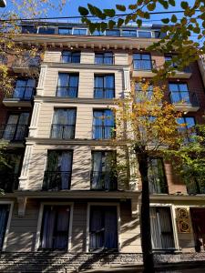 a tall white building with a tree in front of it at CNK Hotel By Millennium Group in Tbilisi City