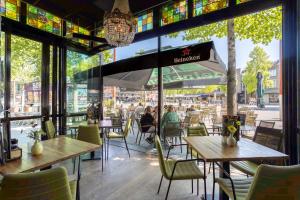 a restaurant with tables and chairs and people sitting at tables at Hotel Hulsman in Venray