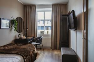 a hotel room with a bed and a desk and a window at Home Hotel Cardinal in Växjö