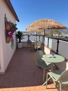 un balcone con tavoli, sedie e ombrellone di La Posada RR junto al Aeropuerto de Málaga a Málaga Altre 32 foto