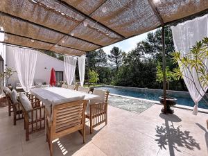un patio con tavolo e sedie e una piscina di La villa dans les arbres - Triangle d'or du Luberon a Ménerbes