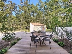 un tavolo e sedie seduti su una terrazza in legno di La villa dans les arbres - Triangle d'or du Luberon a Ménerbes