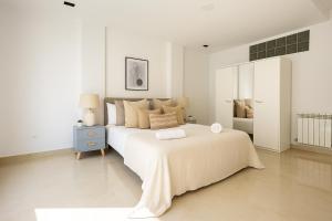 a white bedroom with a large bed and a blue nightstand at Magnifique appartement à Kouba in Kouba