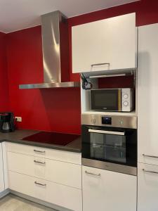 a kitchen with white cabinets and a microwave at L'évasion in Bouillon