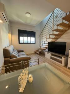 a living room with a couch and a television at A&R Atico Duplex Luxury II in San Sebastián de los Reyes