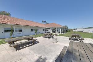un patio con mesas de picnic y un edificio en Fasthotel Well Inn Mâcon sud - un hôtel FH Confort, en Charnay-lès-Mâcon