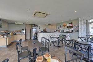 Un restaurante con mesas y sillas y un mostrador. en Fasthotel Well Inn Mâcon sud - un hôtel FH Confort, en Charnay-lès-Mâcon