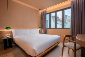 a bedroom with a bed and a chair and a window at Akeah Porto Centro in Porto