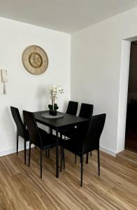 a black dining room table with black chairs and a clock at Gemütliche, frisch renovierte Monteur-& Ferienwohnung in Egeln in Egeln +3 photos