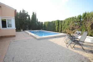 a swimming pool with three chairs next to a house at La casa de las golondrinas in Tángel
