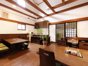 a dining room with a table and a kitchen at Yubaraonsen Yubaranoyado Komeya in Maniwa