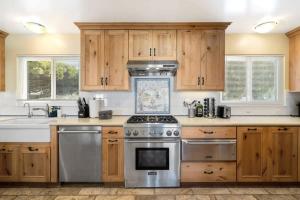 eine Küche mit Holzschränken und einem Edelstahlherd in der Unterkunft @ Marbella Lane - Oceanfront w/ unobstructed views!! in Pacifica