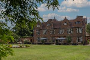 a large brick building with benches and umbrellas in a yard at Castle Bromwich Hall Hotel, BW Signature Collection by Best Western in Birmingham