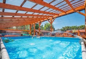 a large swimming pool with a wooden pergola at Domki Forest sauna jacuzzi balia Darłowo Darłówko Rusko in Darłowo