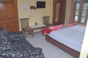 een slaapkamer met een bed, een tafel en stoelen bij Sahil cottage in Chamba +2 foto's