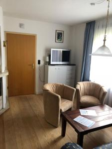 a living room with two chairs and a table at Monteur- Ferienwohnung EG links in Süderende +7 photos