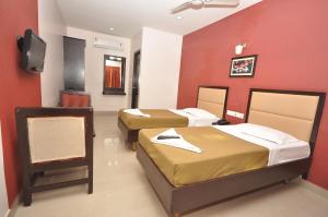 a hotel room with three beds and a flat screen tv at Sri ArulMuthu Residency in Madurai