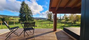 a wooden deck with two chairs and a table on it at Gîtes des Deux Sapins 