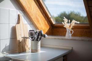 un comptoir de cuisine avec une tasse d'ustensiles sur une fenêtre dans l'établissement Apfel, à Westermarkelsdorf
