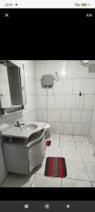 a white bathroom with a sink and a mirror at Quarto com duas Camas Individuais in Gramado