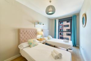 a bedroom with two beds and a window at Alma de Pacifico in Málaga +13 photos