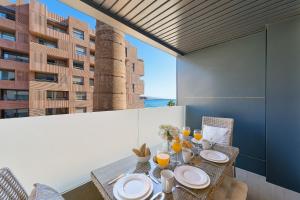 a table with plates and glasses on a balcony with a building at Alma de Pacifico in Málaga