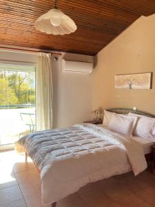 a bedroom with a large bed and a large window at Drosia Hotel in Kato Loutraki