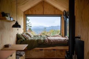 a bed in a room with a large window at Ascella in Llanrwst