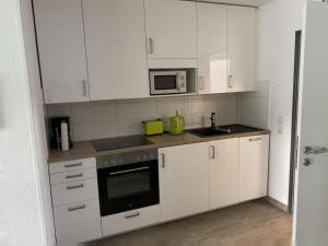 a kitchen with white cabinets and a microwave at Wohnung 70 in Horumersiel