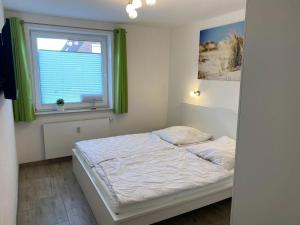 a small bedroom with a bed and a window at Wohnung 70 in Horumersiel