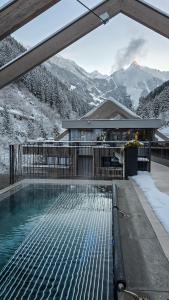 a swimming pool in front of a house with mountains at ZillergrundRock Luxury Mountain Resort in Mayrhofen