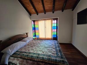 a bedroom with a bed with a colorful quilt and a window at La Kama in Duitama