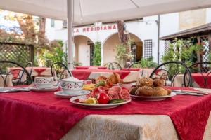 a table with plates of food on a red table cloth at Hotel La Meridiana in Venice-Lido