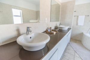 a white bathroom with a sink and a mirror at Waterfront Estate F13 Swakopmund in Swakopmund +33 photos