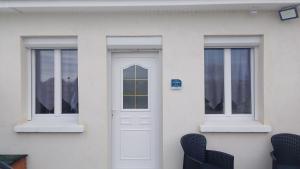 a white house with two windows and a door at gite repos et tranquillité en baie de somme in Cayeux-sur-Mer