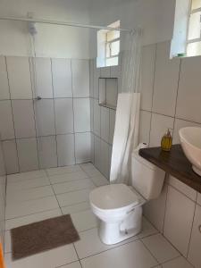a white bathroom with a toilet and a sink at Casa aconchegante ao lado do Parque de Exposições in São Borja